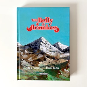 Puede incluir: Un libro de tapa dura titulado The Belly of Aramkass con una ilustración de portada de montañas nevadas bajo un cielo azul brillante. Se acredita a los autores David Pagmar y Pontus Björlin, y el logotipo de Dragonbane está en el centro.