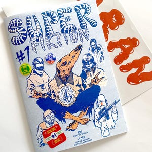 Puede incluir: Una portada de cómic azul y blanca con el título "Super Action #1". La portada presenta una criatura azul y blanca con un diamante en el pecho, una persona con una pistola y una persona con un sombrero rojo. El texto "Art Pontus Ridbäck" y "Story Pontus Ridbäck Mattias Danielsson" está impreso en la portada.