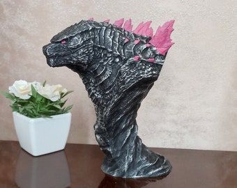 Op de afbeelding: Een zwarte en grijze Godzilla-buste met rode stekels. De buste is gemaakt van een getextureerd materiaal en heeft een gedetailleerd gezicht.