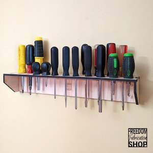 May include: A wooden wall-mounted organizer with a variety of screwdrivers hanging from it. The organizer is made of light wood and has a black border. The screwdrivers are a mix of black, red, yellow, and green.