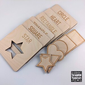 May include: Wooden shapes with cutouts for a shape sorting activity. The shapes include a star, circle, square, heart, rectangle, and triangle. The shapes are labeled with their names.