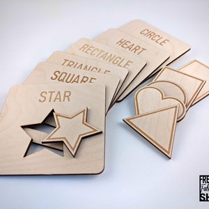 May include: Wooden puzzle pieces with different shapes, including a circle, heart, rectangle, triangle, square, and star. Each piece has the name of the shape written on it.