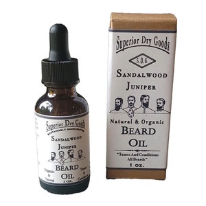 May include: A brown glass bottle with a black dropper top and a label that reads "Superior Dry Goods Sustainably Handcrafted Sandalwood Juniper Beard Oil 1 oz."