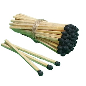 May include: A bundle of wooden matches with black tips, tied together with twine. The matches are arranged in a circular shape, with the black tips facing outward.