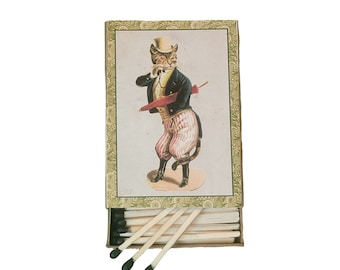 May include: A vintage matchbox with a green and gold design. The front of the box features a cartoon illustration of a cat wearing a top hat and holding an umbrella. The matchbox is open and the matches are visible.