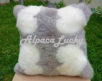 Op de afbeelding: Een grijs en wit alpacavacht kussen met de tekst "Alpaca Lucky" erop gedrukt.