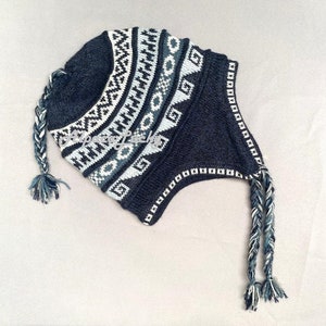 May include: A blue knitted hat with a white and gray geometric pattern. The hat has two long, braided ties.