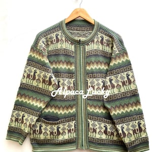 Puede incluir: Cárdigan de lana de alpaca verde con cierre de cremallera y estampado de llama. El cárdigan tiene dos bolsillos en la parte delantera.