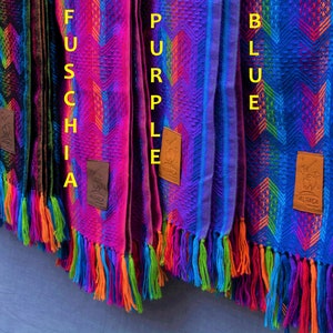 May include: Four alpaca wool scarves in black, fuchsia, purple, and blue with colorful geometric patterns and fringe. Each scarf has a leather tag with the word "Alpaca" on it.