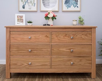 May include: A six-drawer dresser made of light brown wood with silver drawer pulls. The dresser has a simple design and is perfect for a bedroom or living room.