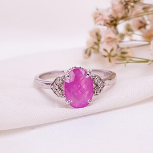 May include: A silver ring with a large oval pink gemstone surrounded by smaller white gemstones.
