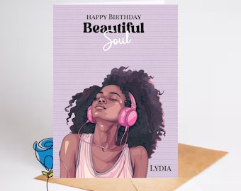 May include: A birthday card with a purple background and a graphic of a woman with brown hair wearing pink headphones. The text "Happy Birthday Beautiful Soul" is at the top of the card and the name "LYDIA" is at the bottom.