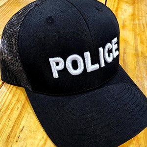 May include: Black trucker hat with a white embroidered "POLICE" patch.