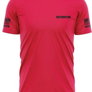 May include: Red short-sleeved t-shirt with the word "INSTRUCTOR" printed on the front and an American flag on each sleeve.