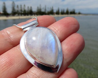 May include: A silver pendant with a pear-shaped moonstone set in a silver bezel. The pendant is on a silver chain.