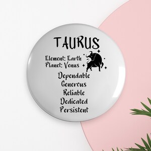 Puede incluir: Botón redondo blanco con texto negro y una silueta negra de un toro. El texto dice "Tauro", "Elemento: Tierra", "Planeta: Venus", "Confiables", "Generosos", "Confiables", "Dedicados", "Persistentes".