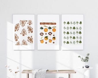 Puede incluir: Tres impresiones artísticas enmarcadas con temática invernal. Una impresión presenta formas de árbol de pan de jengibre marrón, otra muestra rodajas de naranja y vegetación, y la tercera muestra formas de árbol verdes. Las impresiones se exhiben sobre un banco.