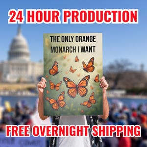 May include: A sign with the text "THE ONLY ORANGE MONARCH I WANT" and illustrations of orange monarch butterflies. The sign is held up in front of a blurred background of a crowd and a building. The words "24 HOUR PRODUCTION" and "FREE OVERNIGHT SHIPPING" are also visible.