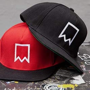 Könnte beinhalten: Zwei Baseballkappen, eine schwarze und eine rote, mit einem weißen Flaggen-Design auf der Vorderseite. Die schwarze Kappe liegt auf der roten Kappe.