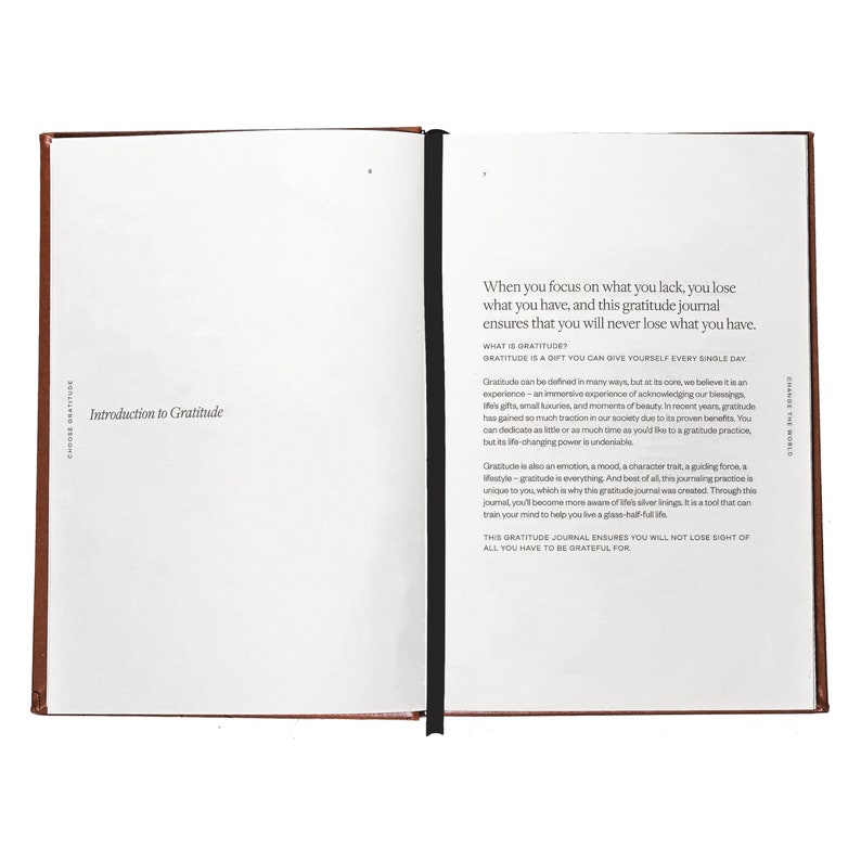 May include: An open brown leather-bound journal with a black ribbon bookmark. The text on the page reads "When you focus on what you lack, you lose what you have, and this gratitude journal ensures that you will never lose what you have. What is Gratitude? Gratitude is a gift you can give yourself every single day."