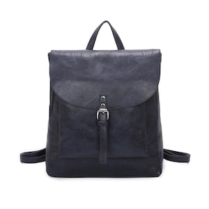 May include: A navy blue backpack with a flap closure and a front pocket. The bag features a top handle, adjustable shoulder straps, and a silver-coloured buckle closure. The material has a textured, leather-like appearance.