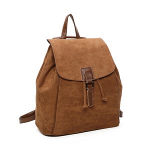 May include: A brown suede backpack with a flap closure and drawstring. The backpack features a top handle and adjustable shoulder straps. The flap has a leather accent with a metal buckle. The bag is approximately 38 cm tall.