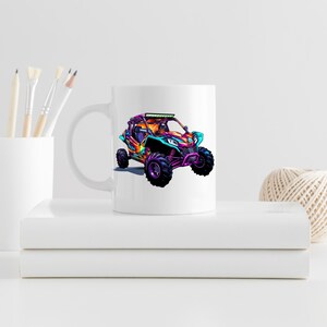 May include: White ceramic mug with a colorful illustration of a pink, blue, and green off-road vehicle with a light bar on the roof.