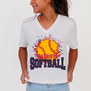 May include: White V-neck t-shirt with a graphic of a yellow softball with red stitching in a red, white, and blue paint splatter design. The text "PATRIOTS SOFTBALL" is printed in navy blue and red.