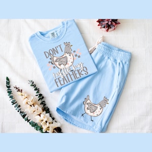 May include: A light blue pajama set with a graphic of a chicken on the shirt and pants. The shirt says "Don't ruffle my feathers".