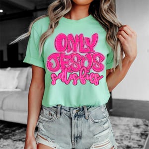 May include: A light green t-shirt with the text "ONLY JESUS satisfies" in pink lettering.