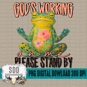 Op de afbeelding: Een digitale download van een groene kikker met bloemenpatronen die mediteert met de tekst "God's working on me please stand by".