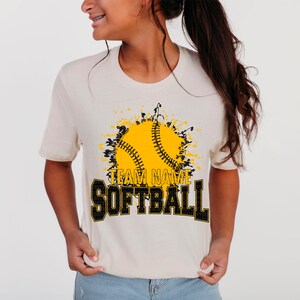 May include: A white t-shirt with a black and yellow graphic of a softball with a splatter effect. The text "TEAM NAME SOFTBALL" is printed in black and yellow.
