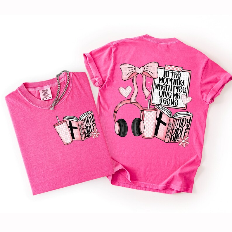 May include: Two bright pink t-shirts. One shirt has a graphic of a book, a drink, and a cross. The other shirt has a bow, headphones, a drink, a book, and the text "In the morning when I rise, give me Jesus."
