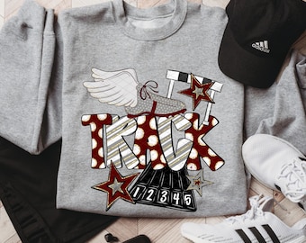 May include: A gray sweatshirt with a "TRACK" graphic featuring a winged running shoe, hurdles, and stars. A black Adidas cap and white sneakers are also visible. The design includes the numbers 1-5.