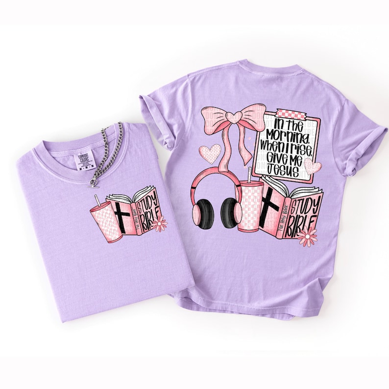May include: Two light purple t-shirts with graphic designs. One shirt features a pink Study Bible, a drink, and a cross. The other shirt has a bow, headphones, a drink, and the text "In the morning when I rise, give me Jesus."