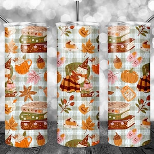 K&ouml;nnte beinhalten: Drei Edelstahlbecher mit einem herbstlichen Design. Das Muster umfasst B&uuml;cherstapel, K&uuml;rbisse, Herbstbl&auml;tter und eine lesende Hexe. Jeder Becher hat einen Strohhalm und einen Deckel.