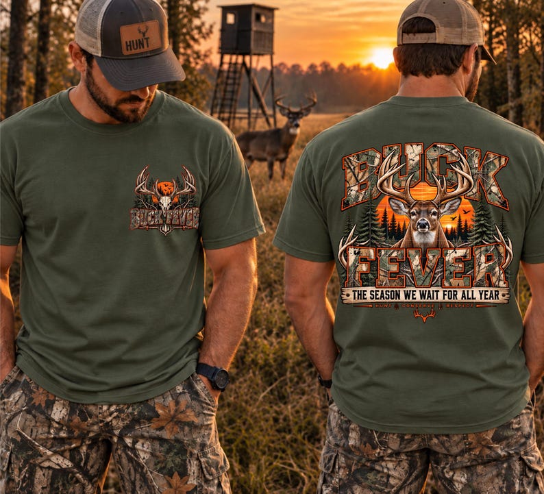 May include: An olive green t-shirt featuring a small graphic on the front chest and a large graphic on the back. Both graphics display a deer head with antlers, camouflage lettering, and the text BUCK FEVER THE SEASON WE WAIT FOR ALL YEAR.