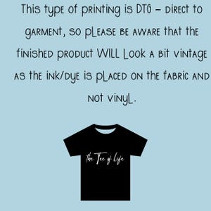 Op de afbeelding: Zwart T-shirt met witte tekst die "the Tee of life" luidt. Dit type print is DTG - Direct to Garment, dus houd er rekening mee dat het eindproduct er een beetje vintage uit zal zien omdat de inkt/verf op de stof wordt aangebracht en niet op vinyl.