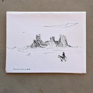 May include: A white rectangular greeting card featuring a black ink line drawing of a desert landscape with rock formations, a lone rider on horseback, and a bird in the sky. The name BETTY PALMER is printed in black ink in the bottom left corner.