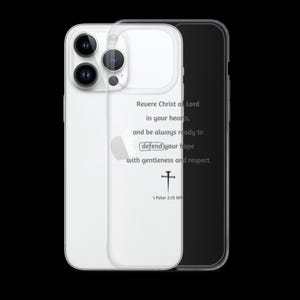 May include: A clear phone case with a printed message. The text reads "Revere Christ as Lord in your hearts, and be always ready to defend your hope with gentleness and respect." A cross symbol is below the text. The phone case is on a black background.