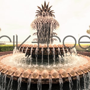May include: A large, ornate fountain shaped like a pineapple with water cascading down its sides. The fountain is surrounded by a circular pool of water and lush greenery.