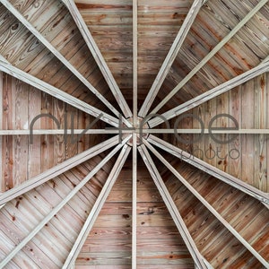 May include: A symmetrical wooden ceiling with a radial design. The ceiling is constructed from light brown wooden planks and beams, creating a starburst pattern. The wood grain is visible, adding texture.