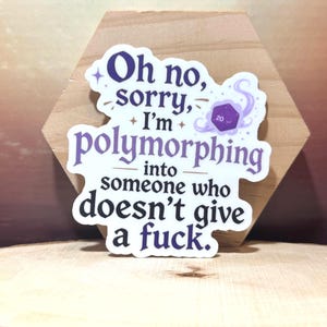 May include: A die-cut sticker with a white background and purple text that reads, Oh no, sorry, I'm polymorphing into someone who doesn't give a fuck. The design includes a small purple twenty-sided die graphic surrounded by swirling purple smoke.