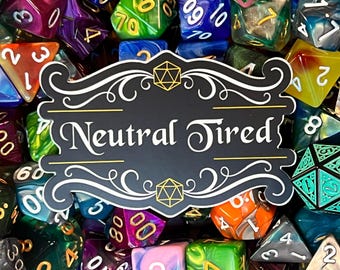 May include: A black and white sticker with a decorative border and the text "Neutral Tired". The sticker is surrounded by a variety of colorful dice.