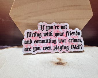 May include: A pink and white sticker with black text that reads "If you're not flirting with your friends and committing war crimes, are you even playing D&D?"