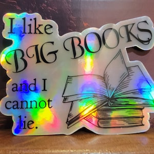 May include: Holographic sticker with the text "I like BIG BOOKS and I cannot lie." The sticker features an illustration of a stack of books with an open book on top. The sticker has a rainbow sheen.
