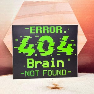 May include: A black square sticker with the text "-ERROR- 404 Brain -NOT FOUND-" in bright green, pixelated font. The sticker is set against a wooden background with a hexagonal shape.