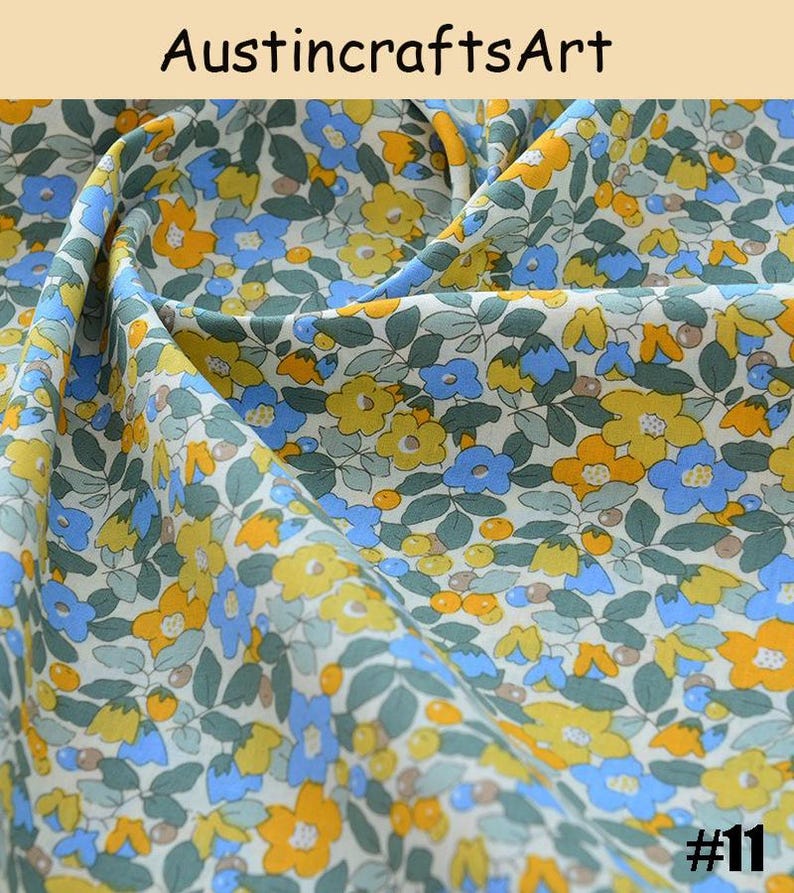 K&ouml;nnte beinhalten: Stoff mit einem dichten Blumenmuster aus gelben und blauen Bl&uuml;ten, gr&uuml;nen Bl&auml;ttern und kleinen runden orangefarbenen Beeren auf wei&szlig;em Grund. Der Text Austin crafts Art und die Nummer 11 sind auf dem Bild zu sehen.