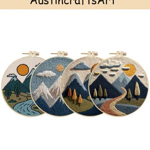 May include: Four round embroidery hoops featuring mountain landscape designs. Each hoop showcases a different scene with mountains, trees, a sun, and a river or path. The text "AustincraftsArt" is at the top.
