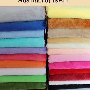 Könnte beinhalten: Zwei Stapel gefalteter Plüschstoffquadrate in einer Vielzahl von Unifarben, darunter Grau, Blau, Türkis, Lila, Rot, Orange, Weiß, Grün, Gelb, Braun, Pink und Schwarz. Der Text AustincraftsArt ist oben im Bild zu sehen.